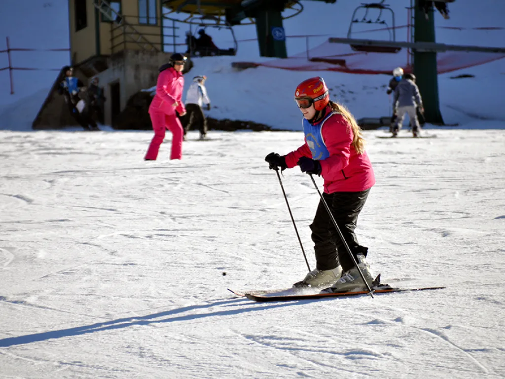 Skifahrerin in pinker Jacke fährt an der Talstation vorbei.